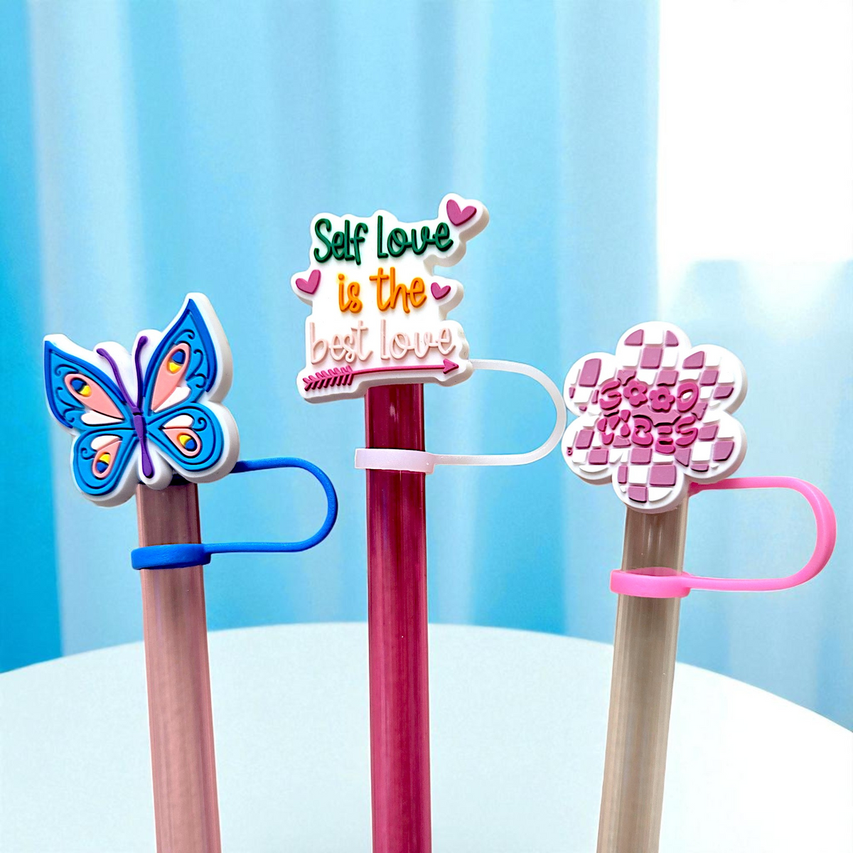 Biddlebee Three colorful straw topperd with decorative ends on a light blue background