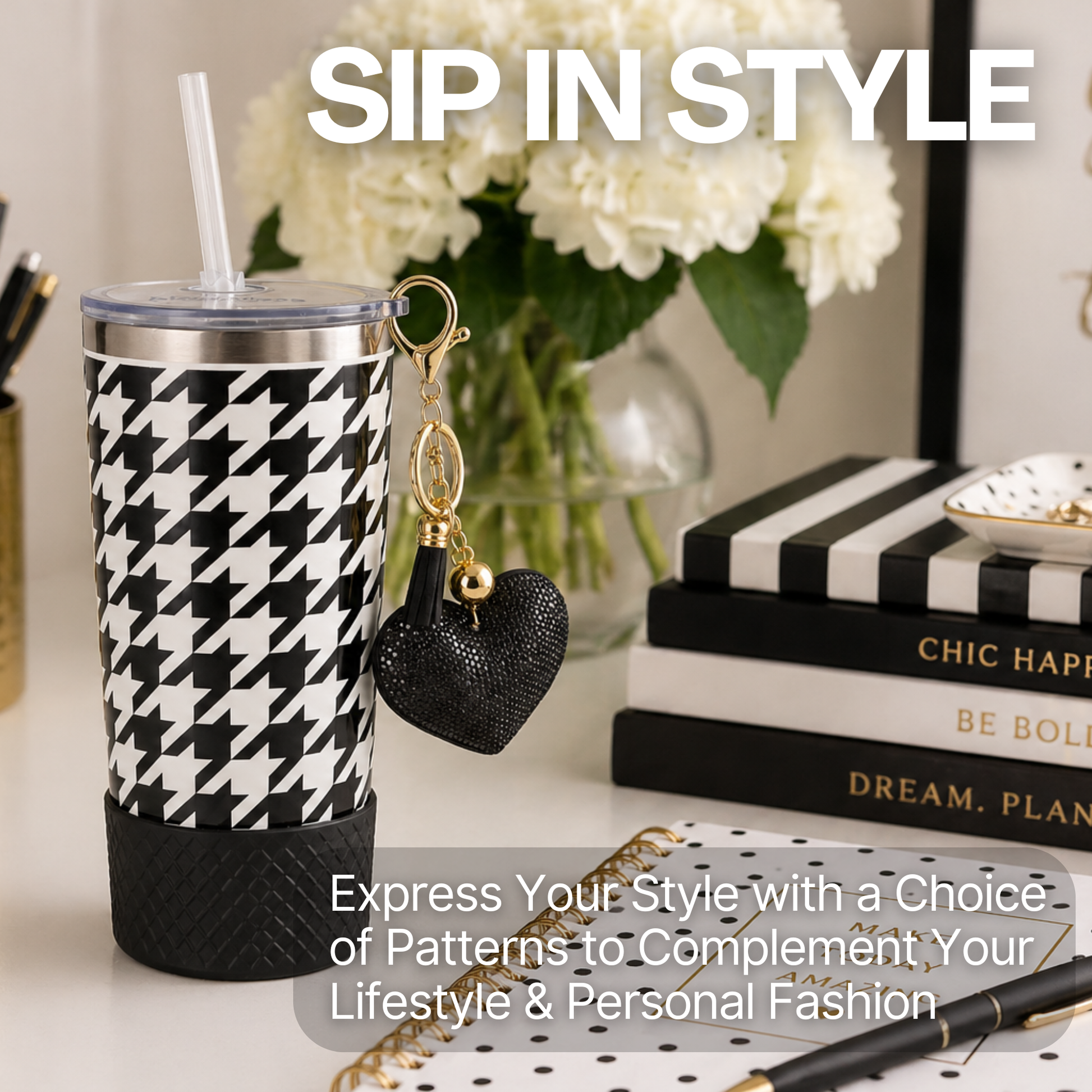Biddlebee 20oz signature black and white charm tumbler with a heart keychain on a desk with books and flowers.