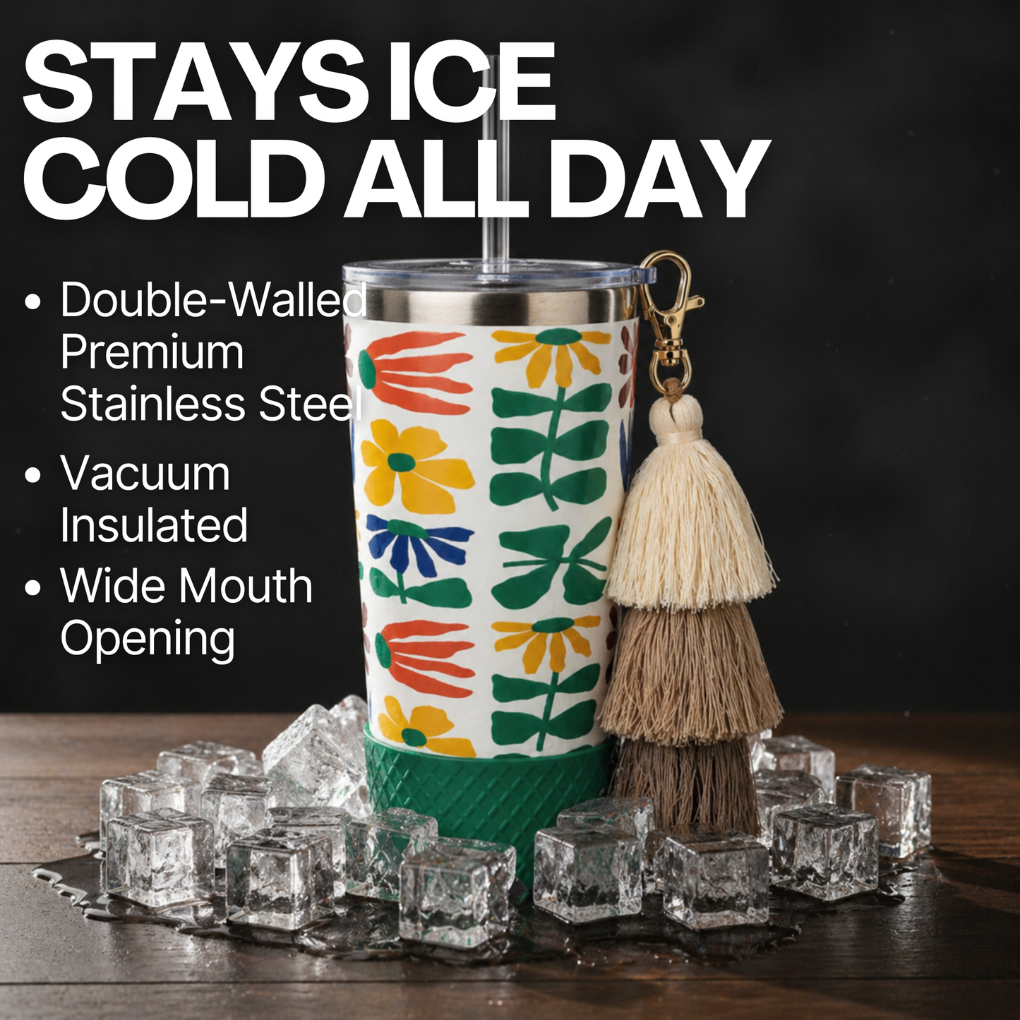 Biddlebee 20oz retro floral charm tumbler with green silicone boot, brown ombre tassel charm and easy sip straw lid  with ice cubes double wall insulation charm on a wooden surface.