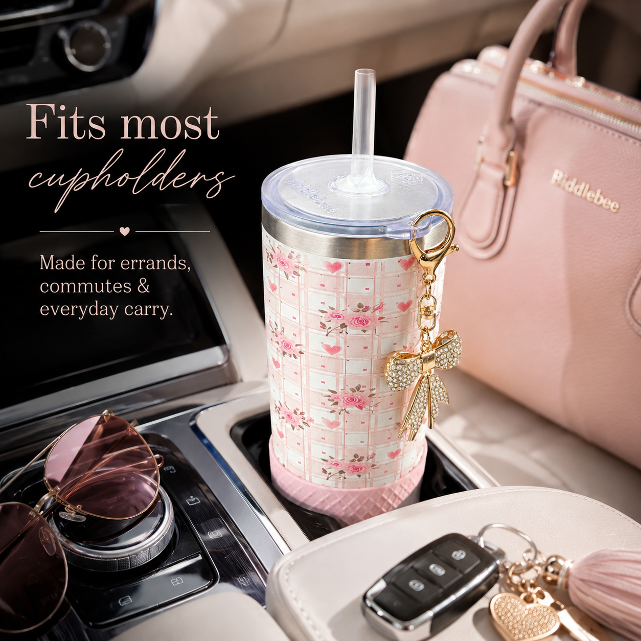 Floral-patterned tumbler with a keychain in a car cupholder, next to sunglasses and a pink handbag.