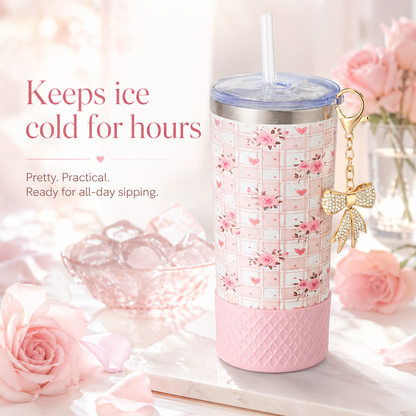 Pink floral tumbler with bow charm on a decorative surface with pink roses.