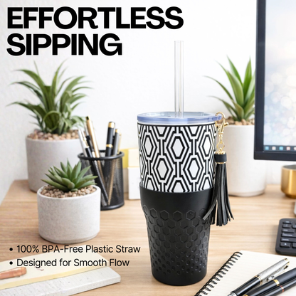 Biddlebee 30oz Black & White Charm tumbler with a straw lid, vegan tassel and silicone boot on a white background on a desk with plants and office supplies.