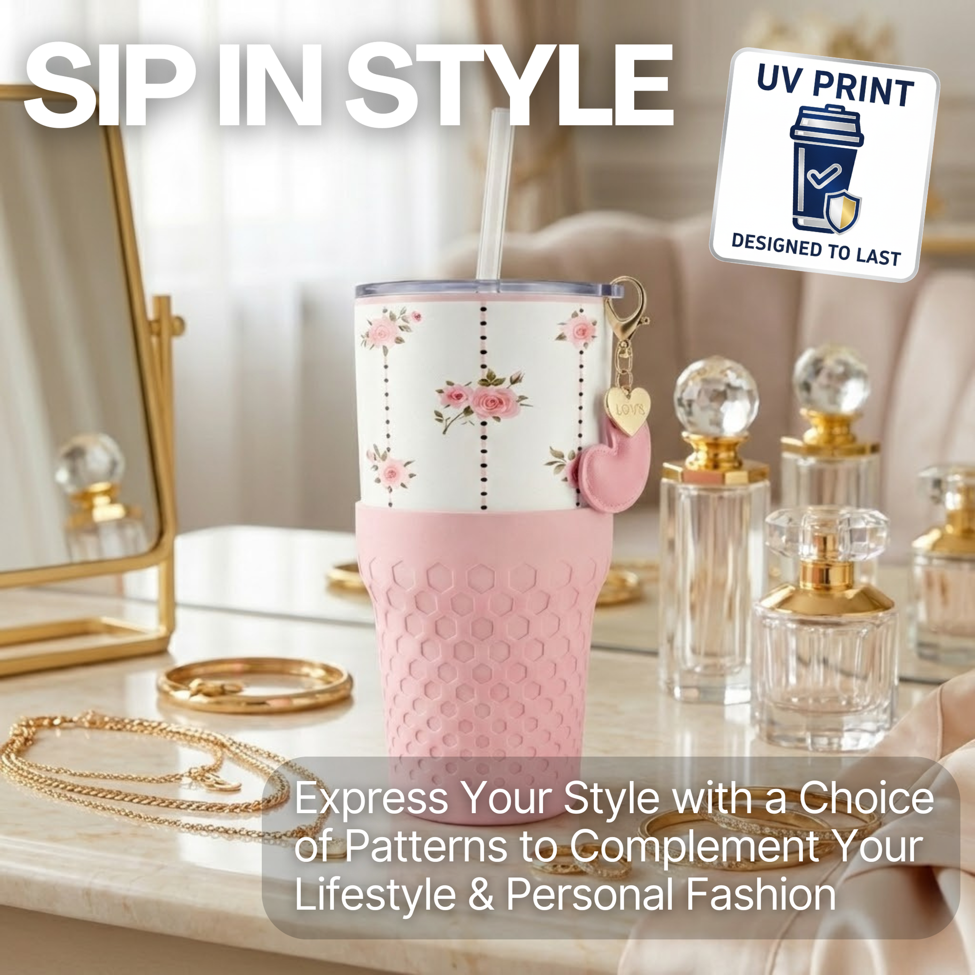 Biddlebee 30oz pink roses charm tumbler with easy sip straw lid, removable heart charm, and protective silicone boot on a vanity table with perfume bottles and jewelry.