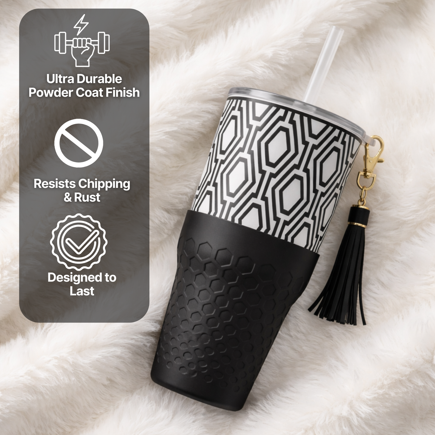 Biddlebee 30oz Black & White Charm tumbler with a straw lid, vegan tassel and silicone boot on a white background on a white fluffy surface, with durability features displayed.