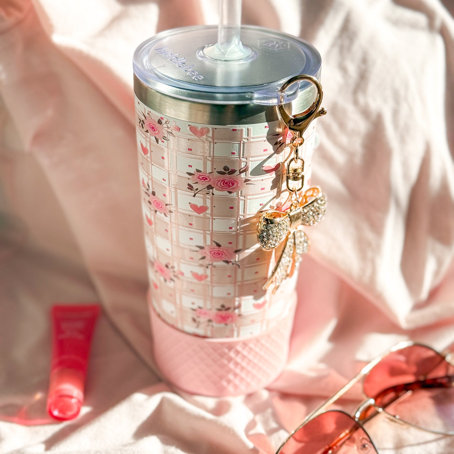 Tumbler with floral design and keychain on a soft pink background