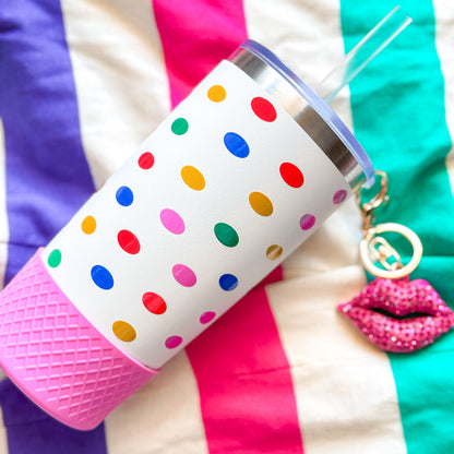Colorful Biddlebee 30oz polka dot charm tumbler with a pink base on a multicolored striped background