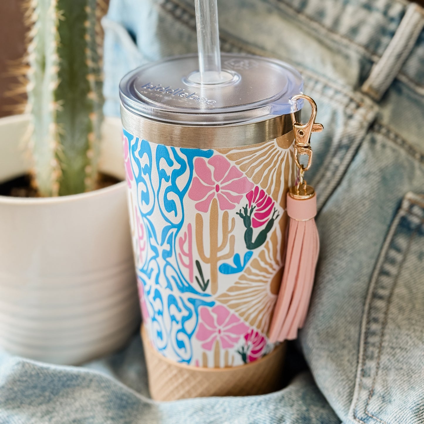 Biddlebee 20oz charm tumbler in desert dreams southwestern boho pattern  and pink tassel on denim surface